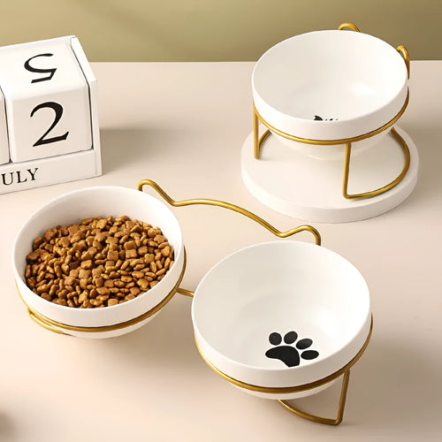 White ceramic pet bowl with cat paw print design on a black iron frame stand with cat ear details.