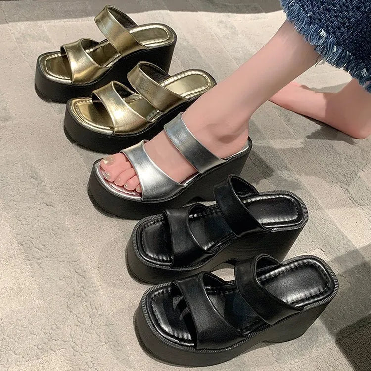 Women's black wedge platform slippers with a square toe on a white background.