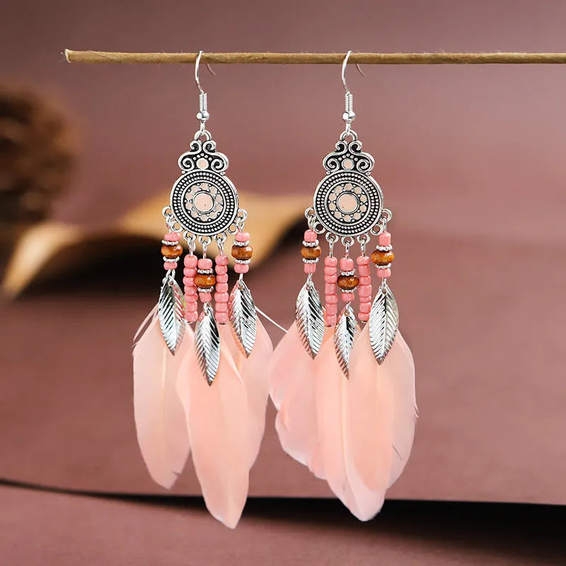 A pair of round drop leaf-shaped feather earrings in a chosen colour, showing Bohemian pattern details.