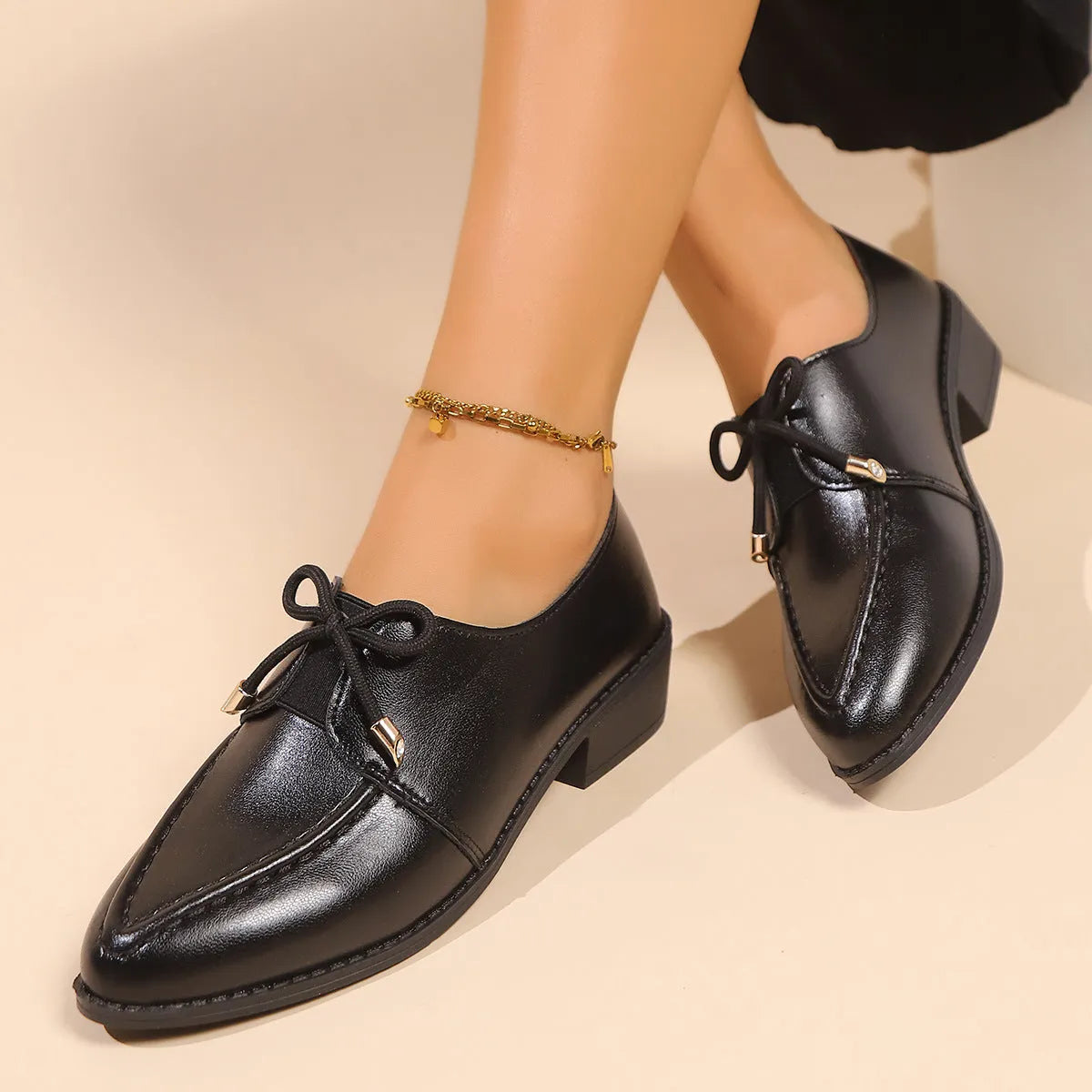 Women's brown leather-look shoes with a decorative bow detail on a flat rubber sole
