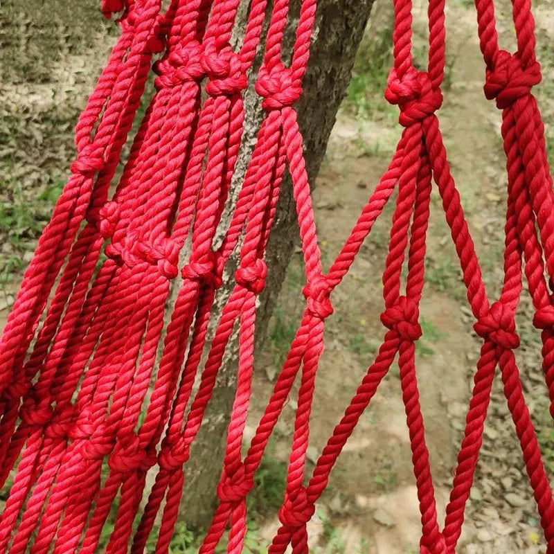 Outdoor nylon rope mesh hammock hanging between two trees, showing its woven construction and spacious 1.1m by 2.1m size.