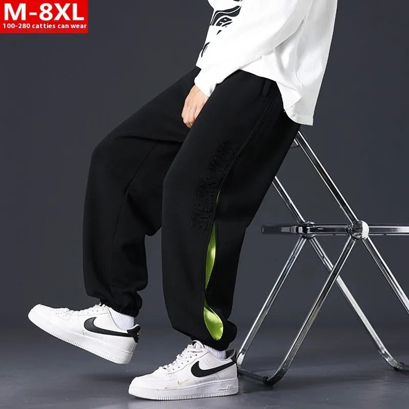 Man wearing loose grey-green trousers with stitching print detail and ankle banding.