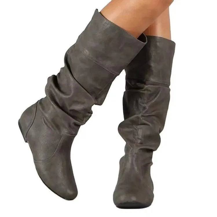 Women's black slip-on flat boots with round toe and high cylinder design on a neutral background.