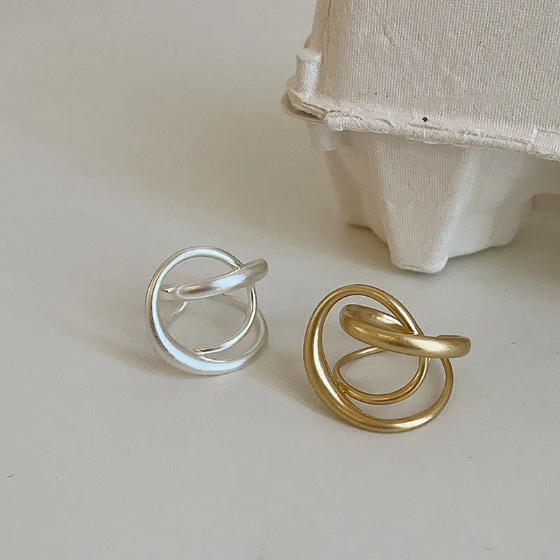 Geometric open ring for women with 3D interlaced matte metal design in gold or silver.