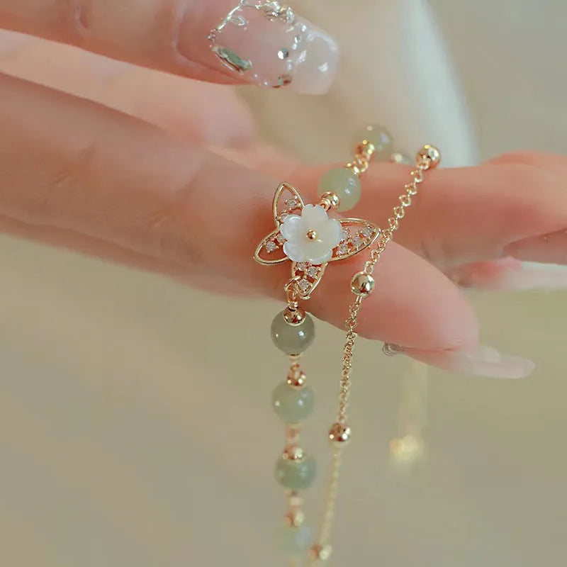 Yellow gold electroplated copper bracelet with a geometric bells of Ireland butterfly and Hetian jade design for women.