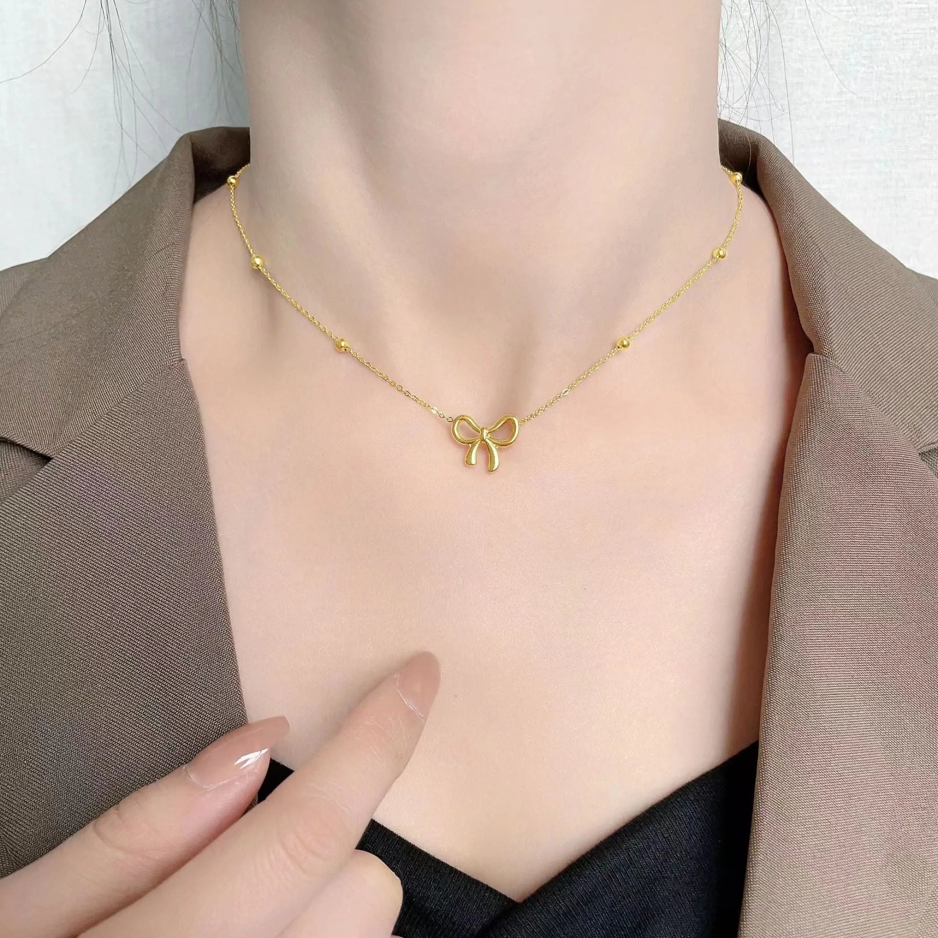 Gold electroplated bow necklace on a titanium steel cross chain, adjustable from 41 to 50 cm.