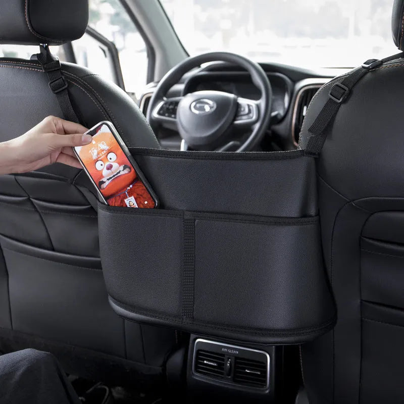 Black leather car seat storage bag with a carbon fibre pattern, shown between vehicle seats.