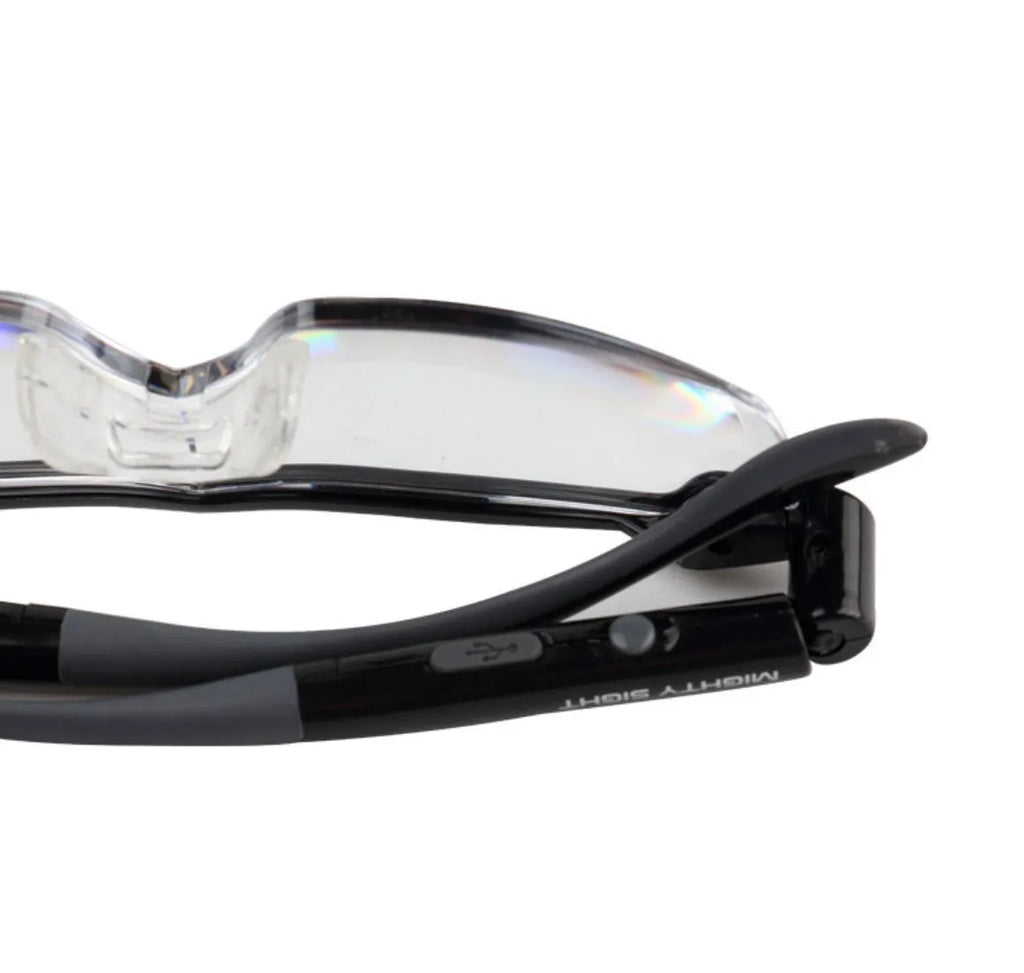 Transparent black USB LED light reading glasses on a desk