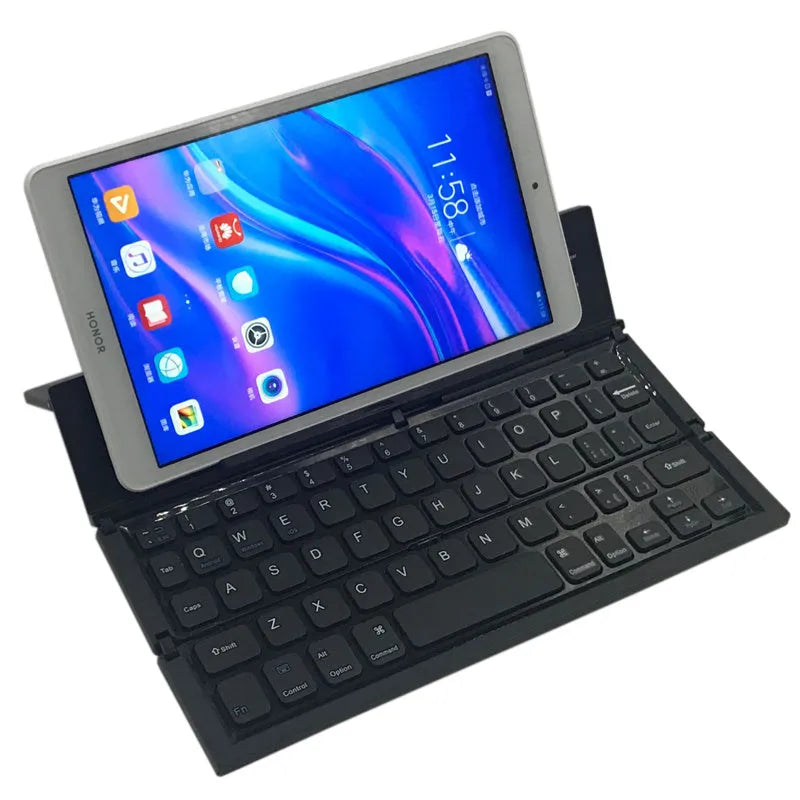 Black folding wireless Bluetooth keyboard unfolded next to tablet showing mini keyboard size