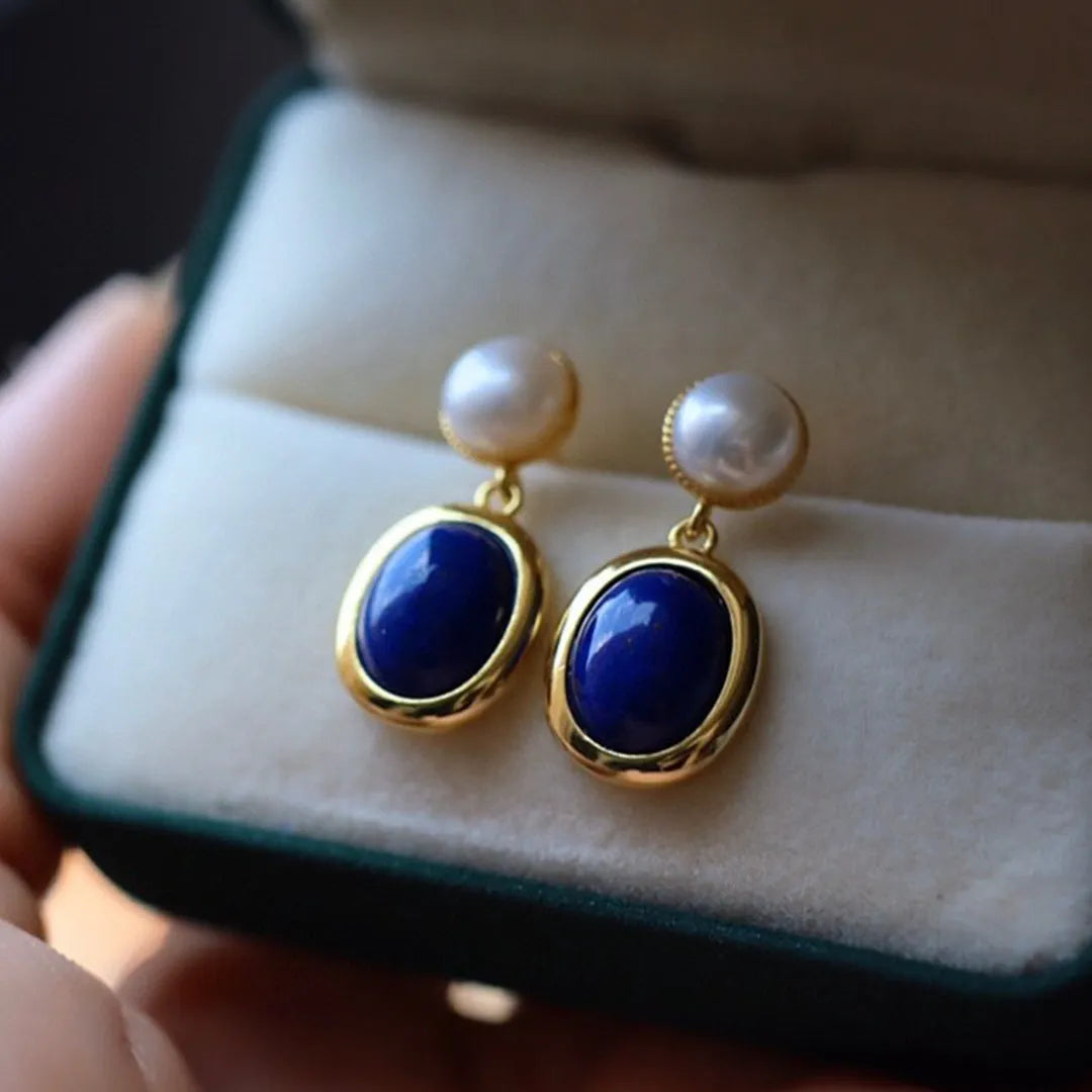 A pair of simple stud earrings with a blue lapis lazuli pearl set in sterling silver.