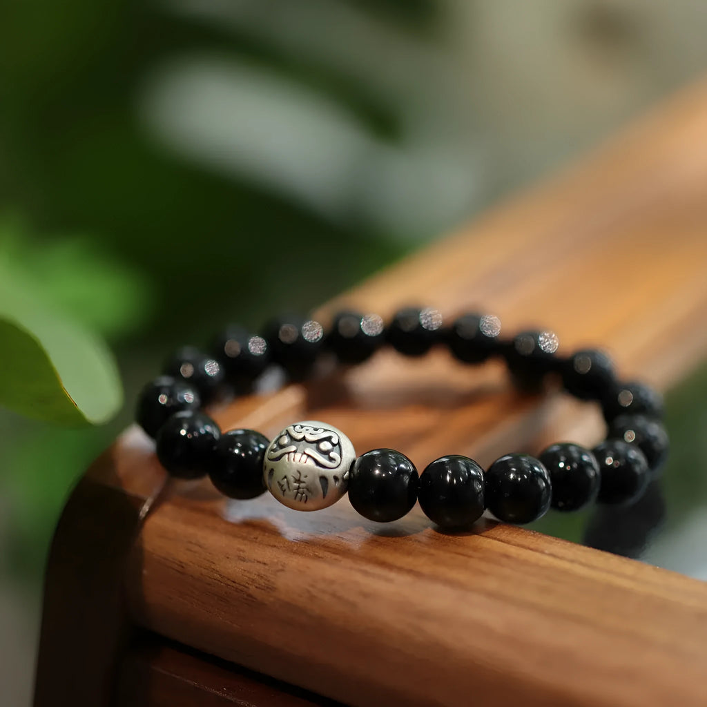 Close-up of a women's black agate bead bracelet with a sterling silver clasp on a wrist.