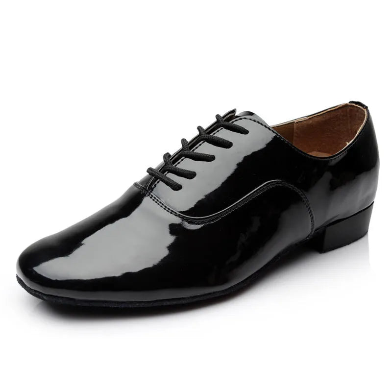 Men's black dancing shoes with a synthetic leather upper and calf leather sole, shown on a studio floor.