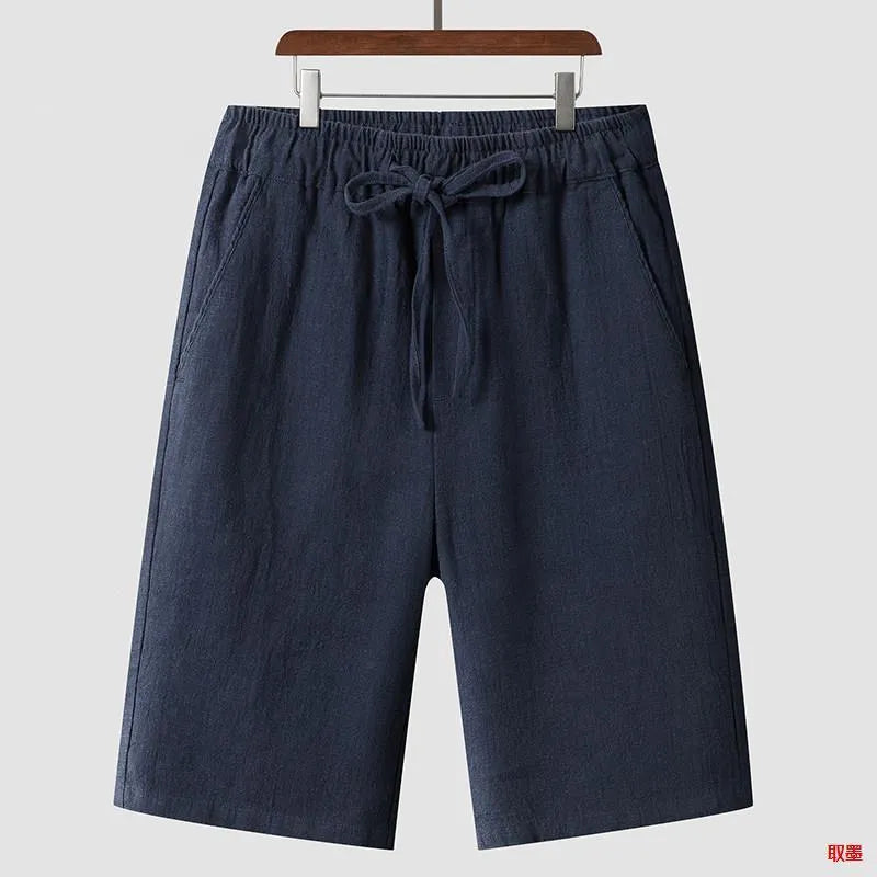 Men's beige linen casual shorts with loose cropped fit and elastic waistband laid flat