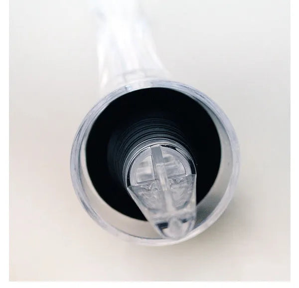 Compact clear acrylic wine aerator with a stainless steel filter insert on a wooden table.