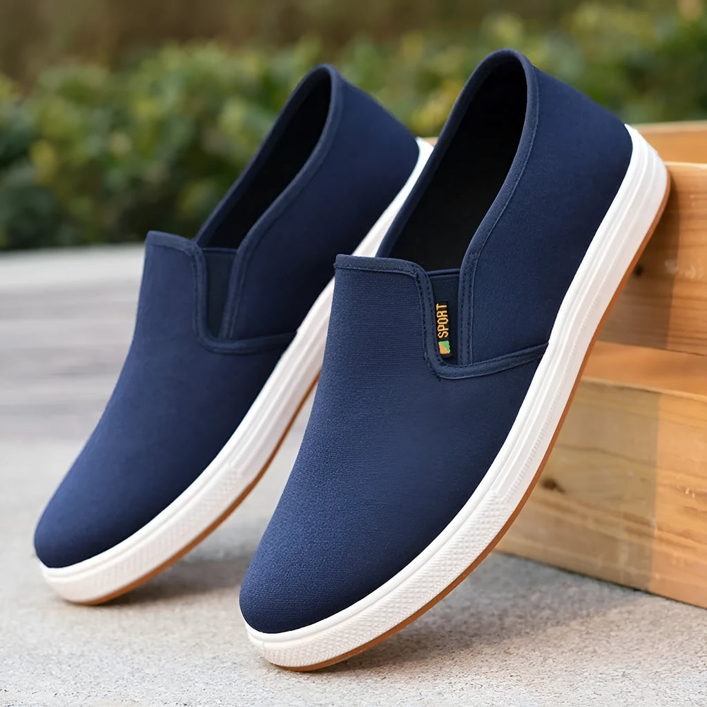 Men's black low-top slip-on canvas shoes with a round toe and composite sole on a white background.