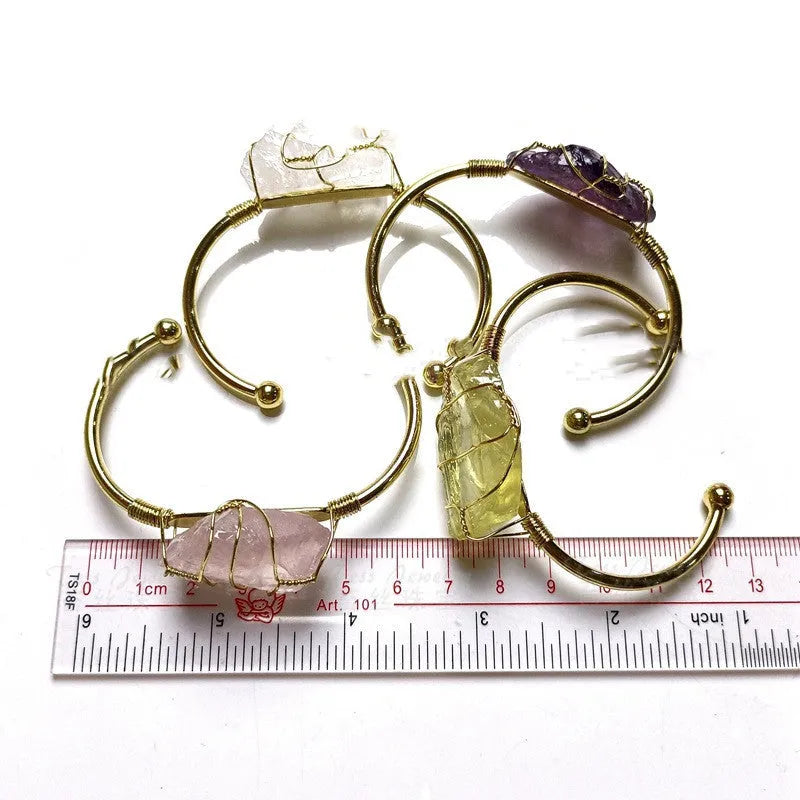 Gold winding geometric bracelet with unshaped rough natural crystal stones on a wrist.
