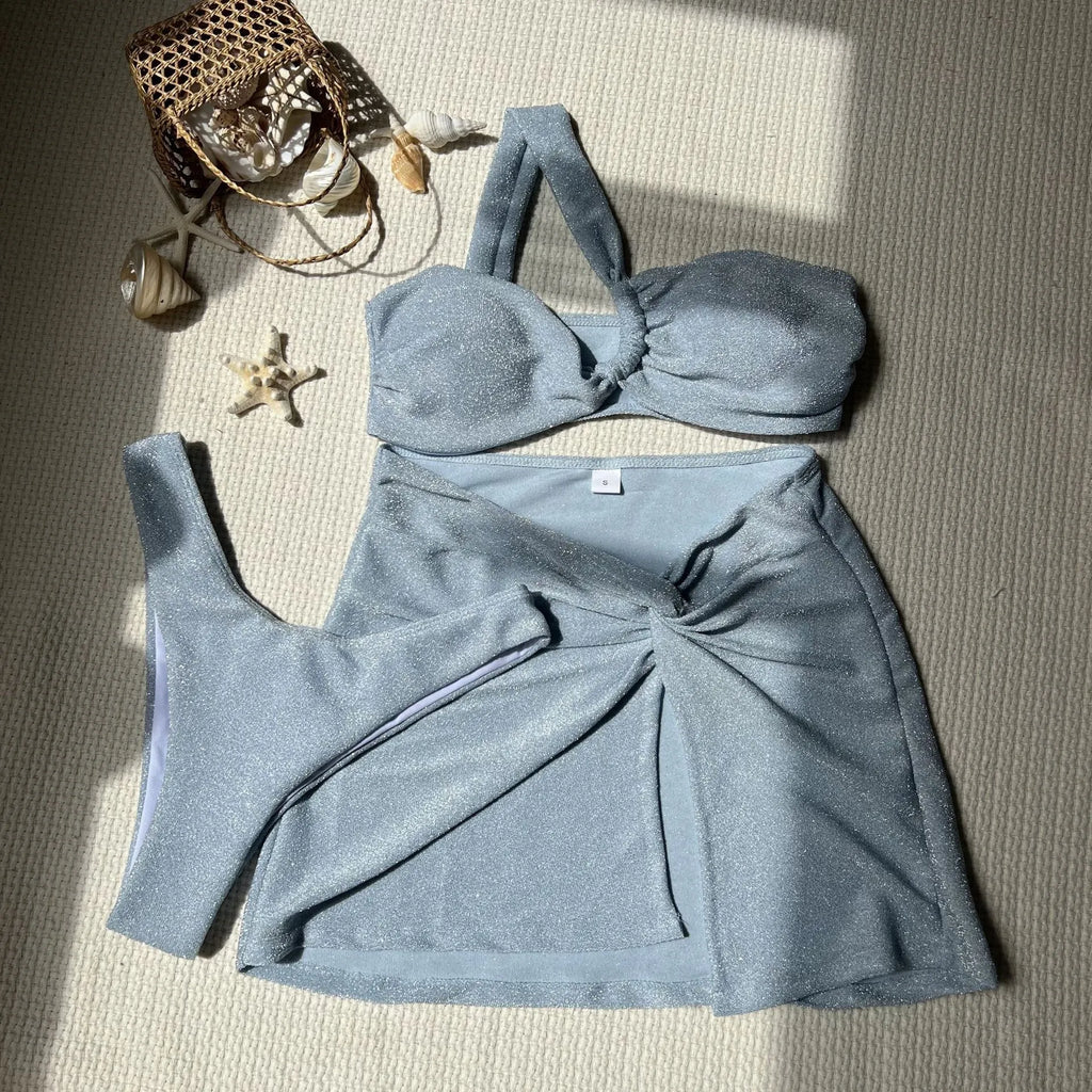 Women's light green one-shoulder swimsuit top with matching briefs and skirt laid flat.