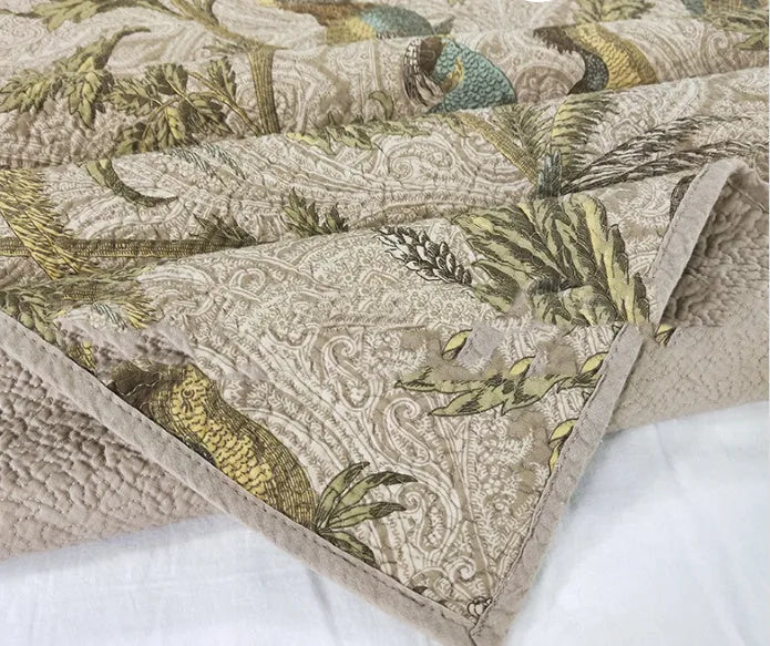 Blue American floral and bird print cotton quilted bedspread set with matching sheet on a bed.