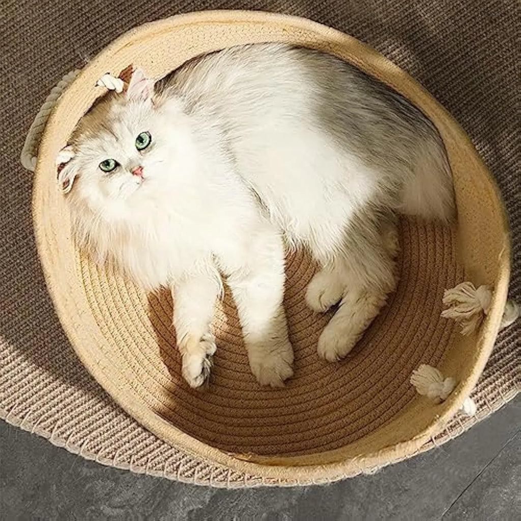 A rectangular wicker cat bed basket with a corrugated cardboard scratching surface on its side.