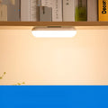 Compact white magnetic table lamp with a large luminous surface and USB charging port.
