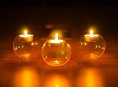 Handmade clear round hollow glass candle holder in three size options on wooden table