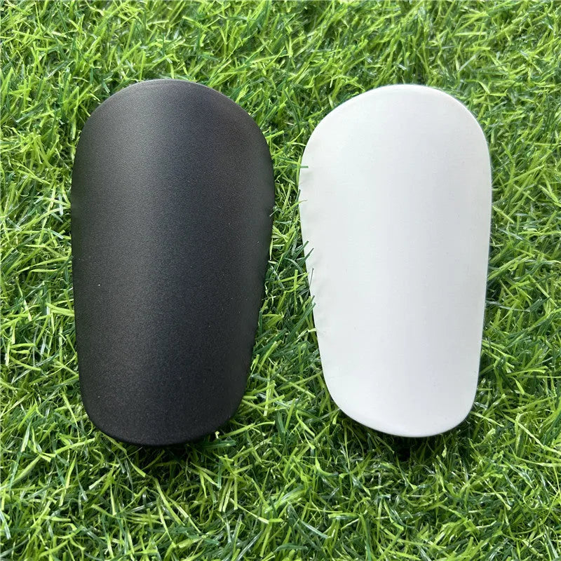 Extra small black and white plastic football shin guards measuring 8x5cm and 10x6cm