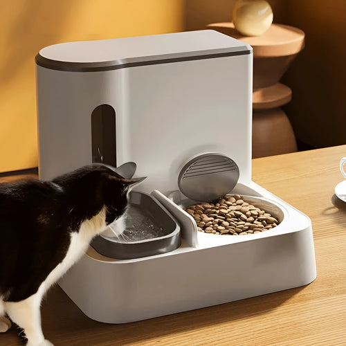 Grey automatic cat feeder and water dispenser station with integrated double bowls on a wooden floor.