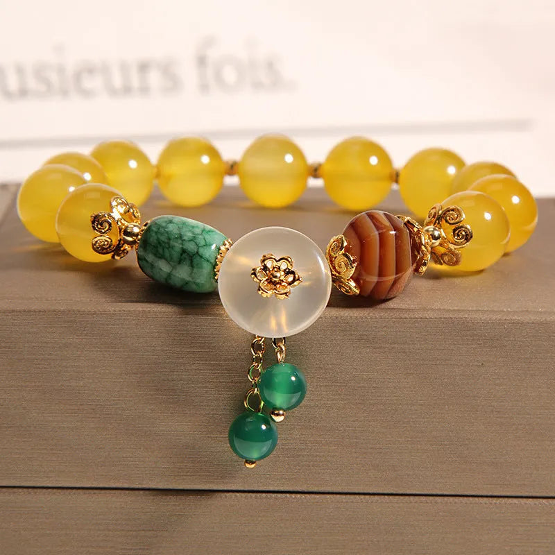 Yellow agate crystal bracelet with gold silk cord and adjustable sliding knot on a wrist.