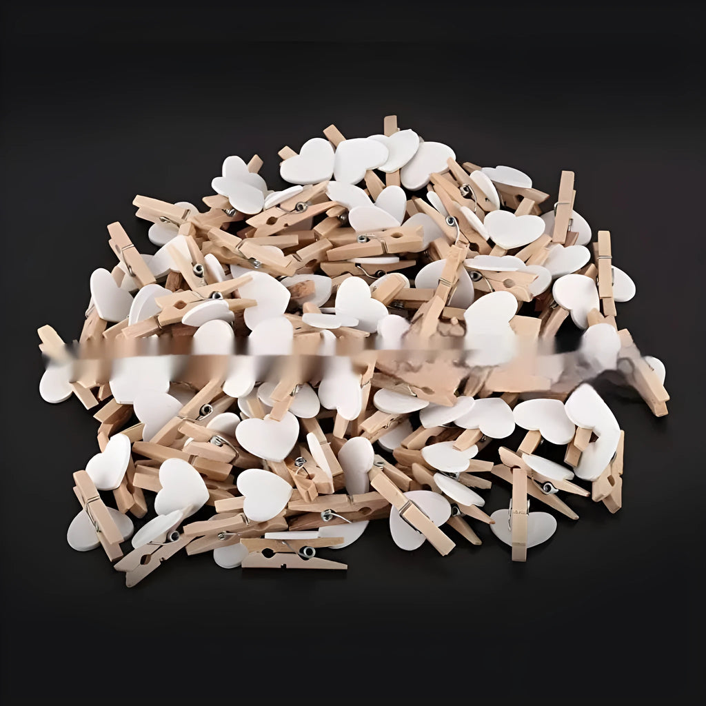 Five small handmade solid wood heart-shaped clips in assorted colours on a white surface.
