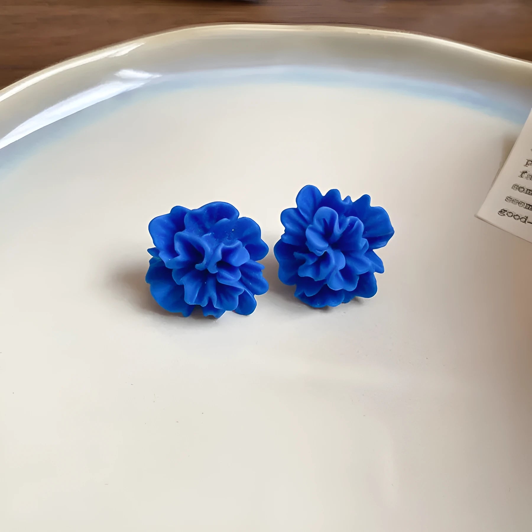Women's geometric earrings with blue resin flowers on cloth material featuring silver needle elements
