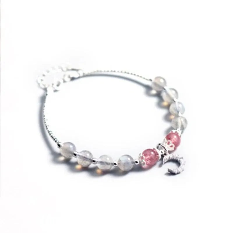 Handmade adjustable moonstone bracelet with crescent moon charm and crystal bead on wrist.