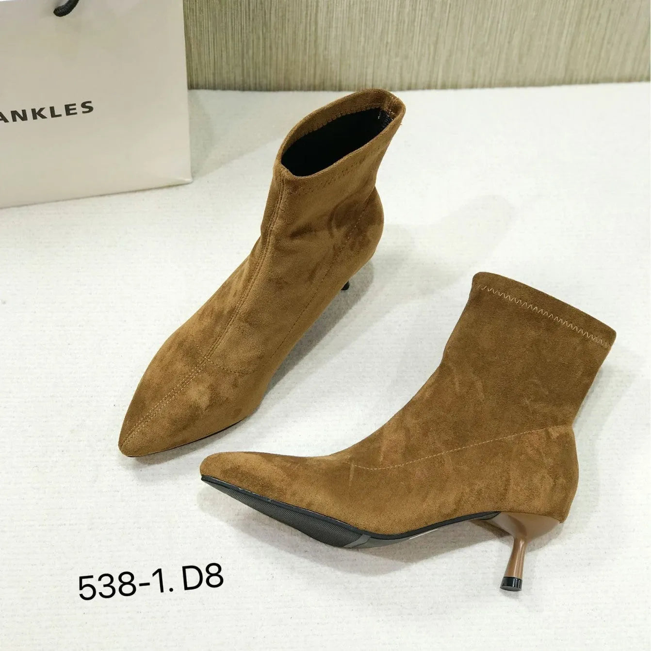Black pointed toe ankle boots with a high stiletto heel on a woman's foot.