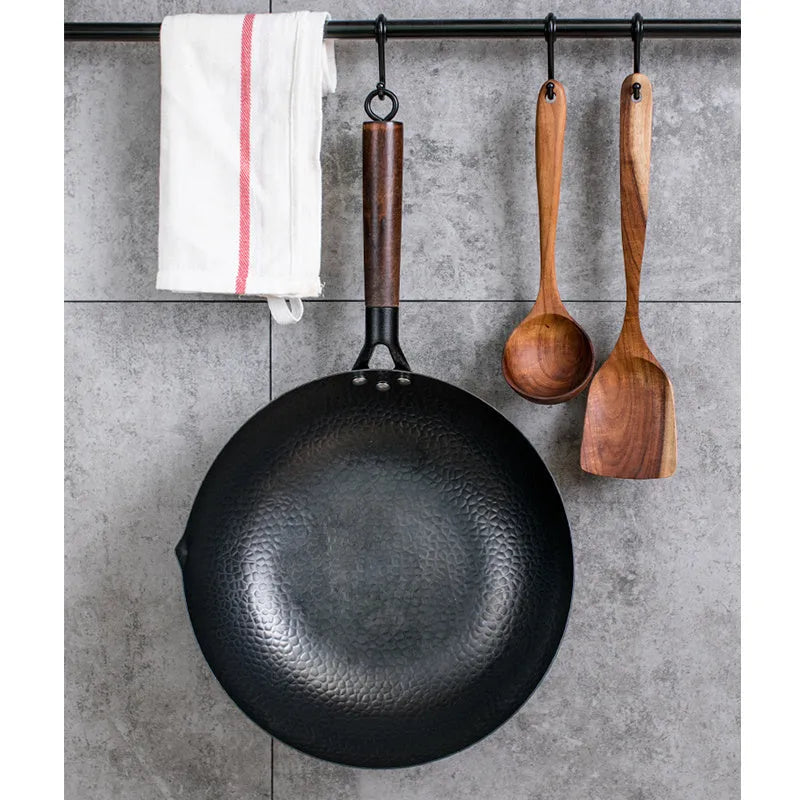 Black traditional iron wok pan with wooden handle and induction base