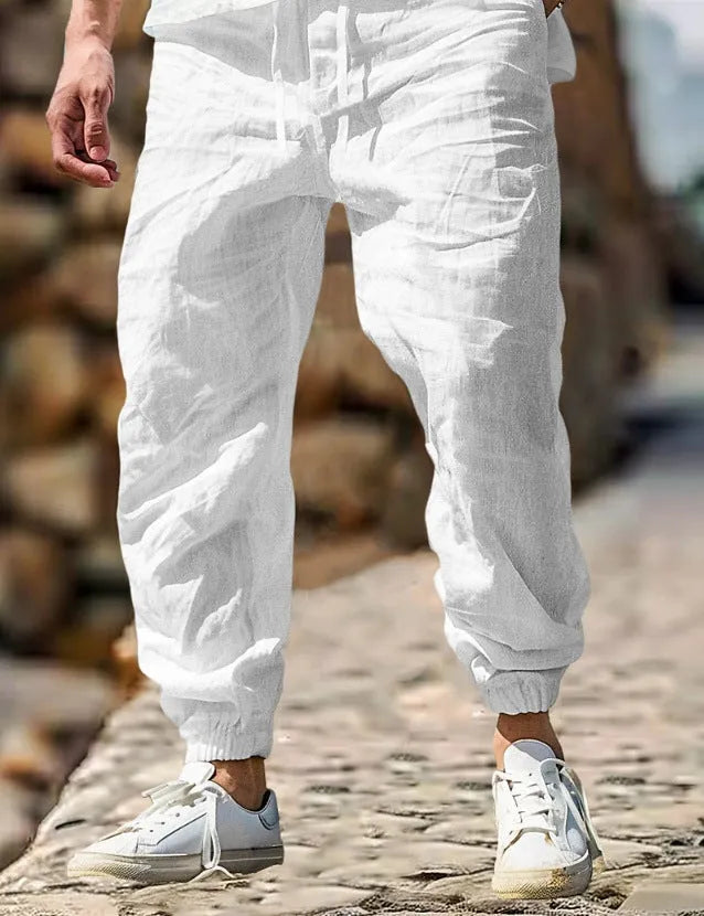 Men's beige straight leg linen trousers with elastic waistband laid flat