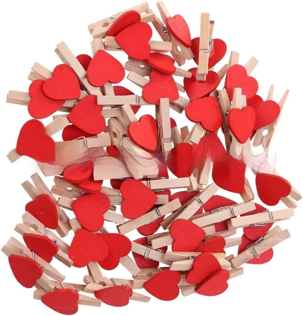 Five small handmade solid wood heart-shaped clips in assorted colours on a white surface.