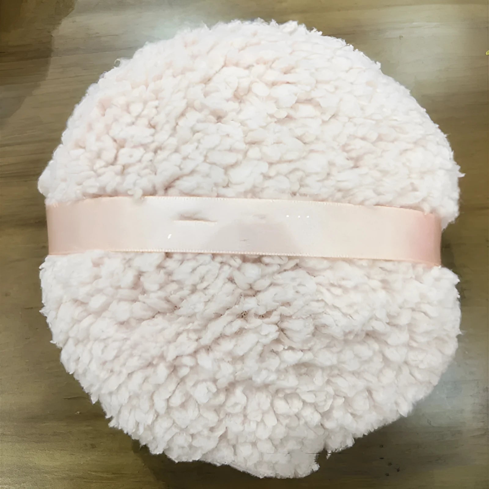 Oversized plush dry powder puff measuring 150x75mm for loose powder application in white skin colour