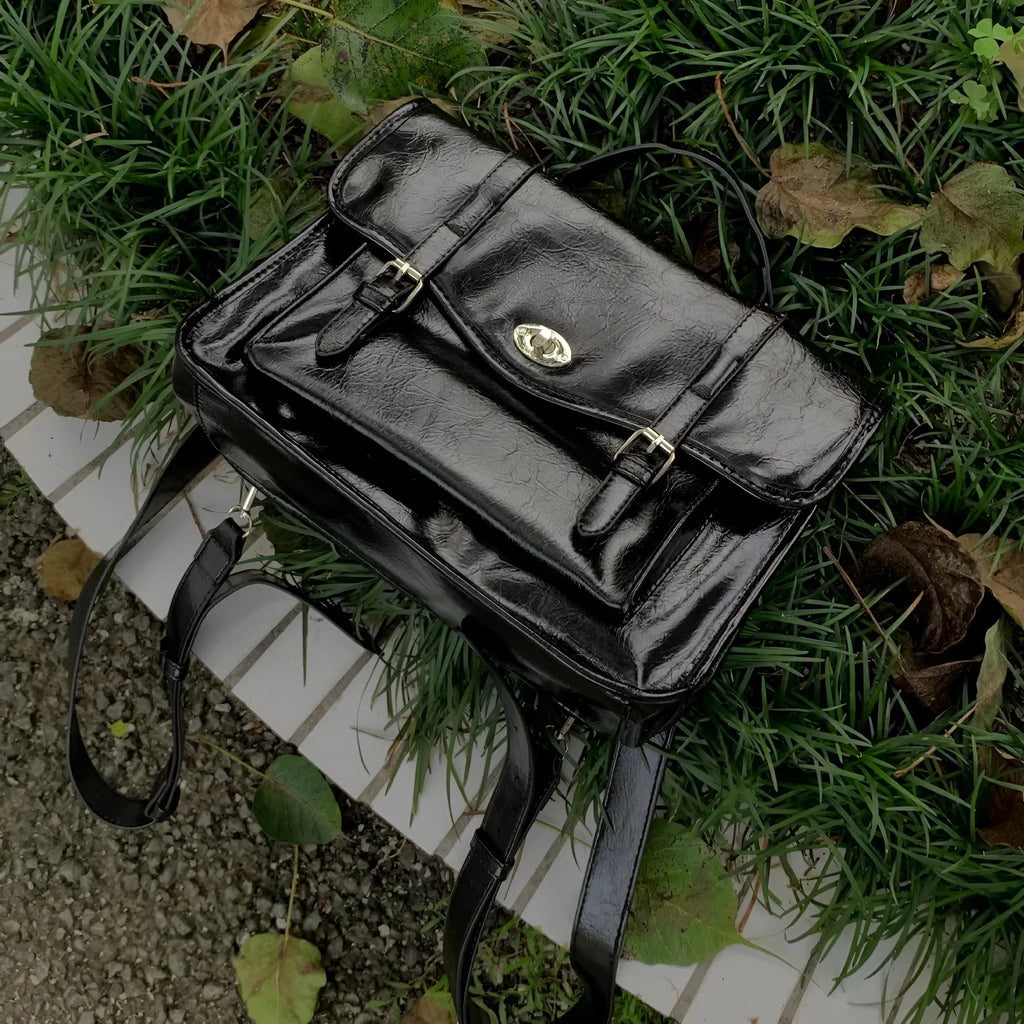 Black college messenger bag with oil wax leather texture showing front compartment and cross-body strap
