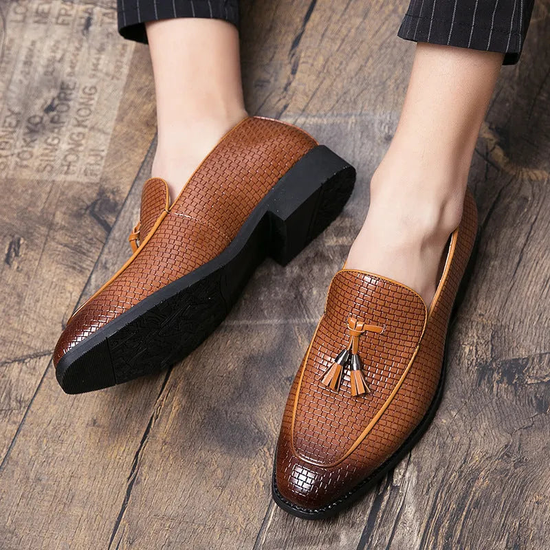 Men's black pointed toe slip on loafers with a tassel detail on the front, shown on a plain background.