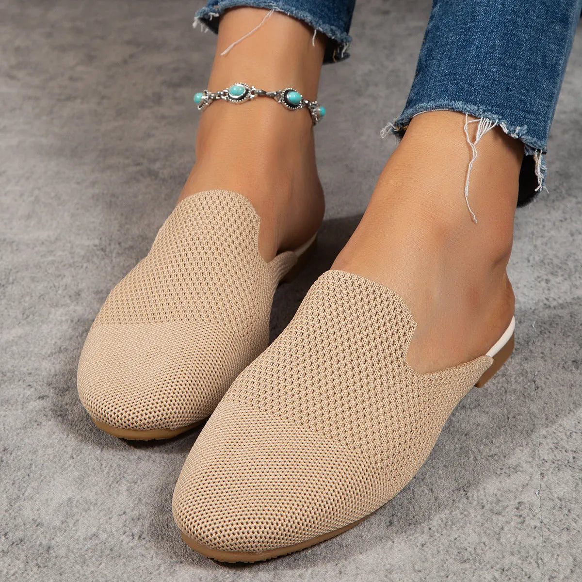 Apricot coloured mesh slip-on sandals with a round toe and flat rubber sole on a wooden floor.