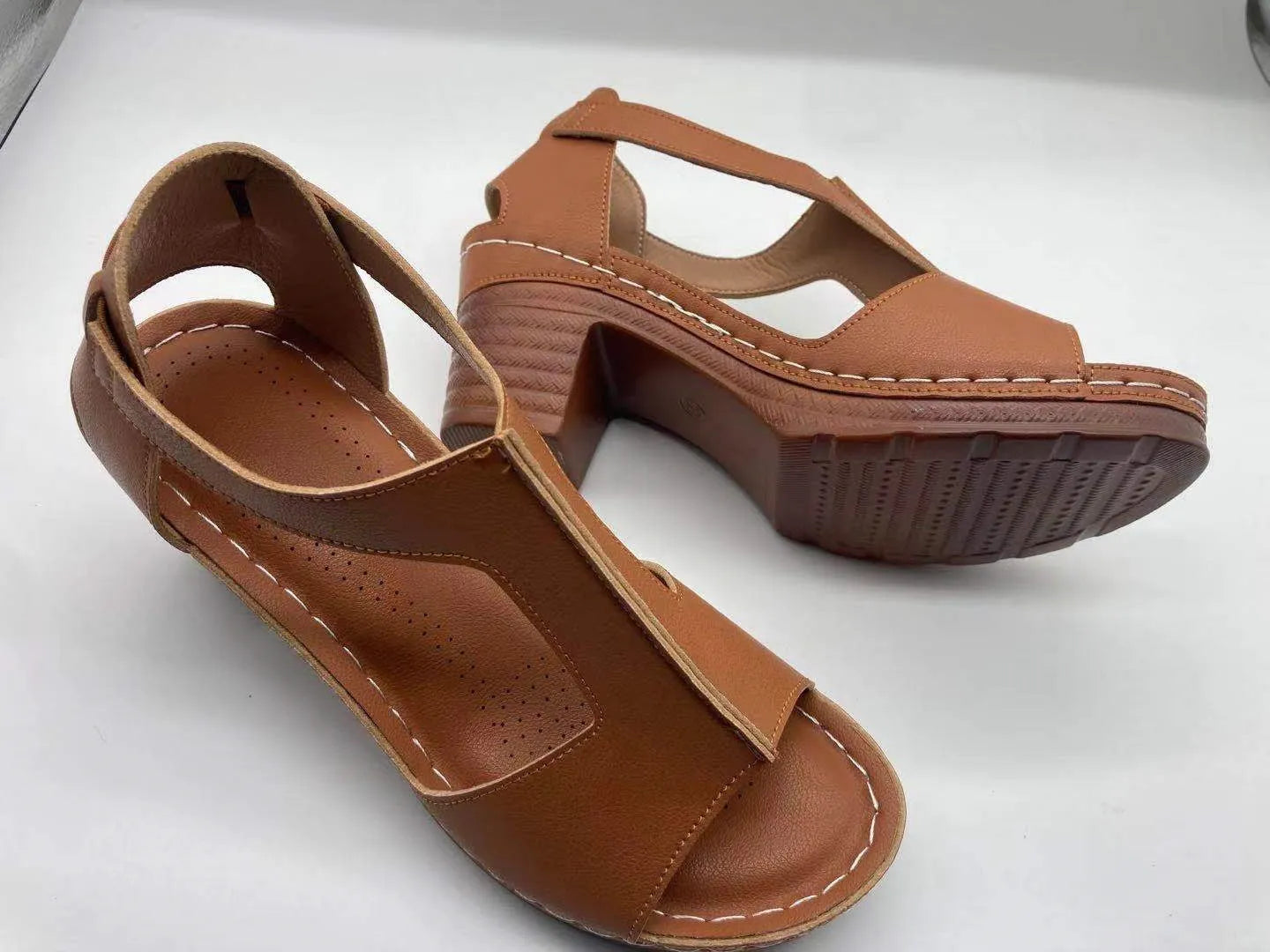Plus size women's beige open toe wedge sandals with a buckle strap and low heel on a white background.