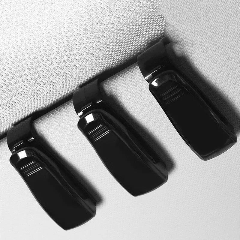Black plastic clip for holding glasses and cards on a car sun visor.