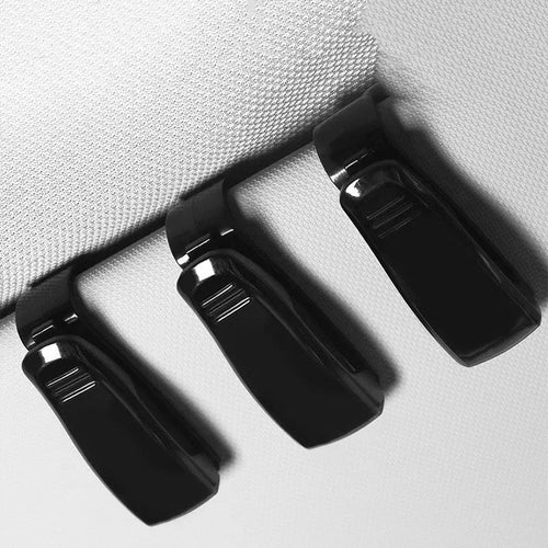 Black plastic clip for holding glasses and cards on a car sun visor.