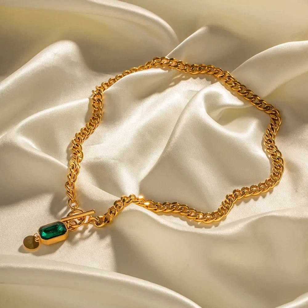 Gold electroplated titanium steel pendant necklace with geometric design and emerald zircon accents on Cuban link chain