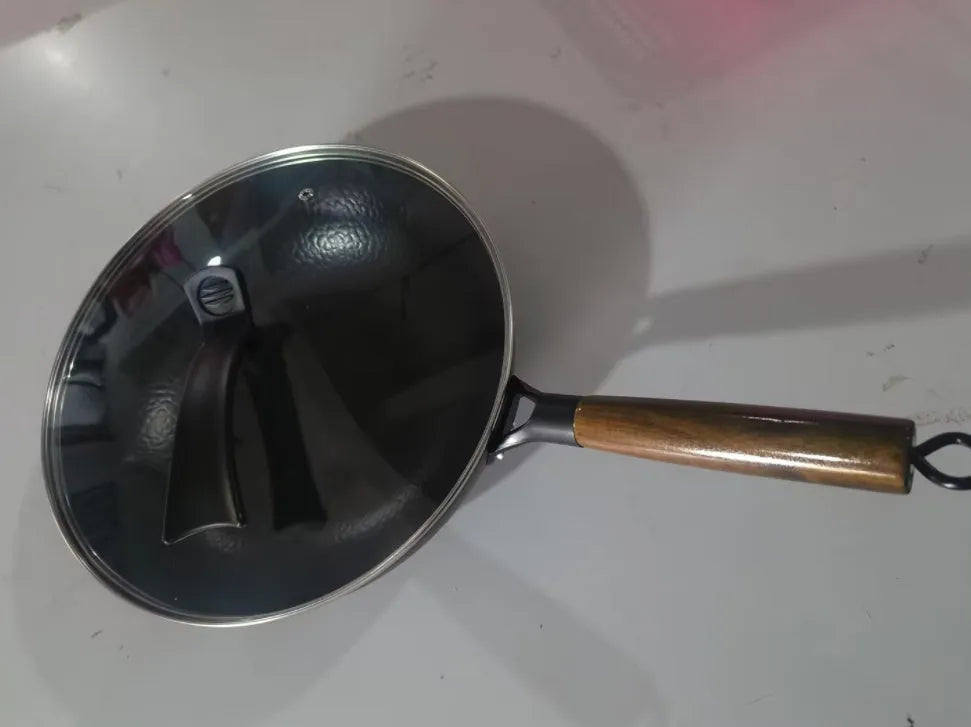 Black traditional iron wok pan with wooden handle and induction base