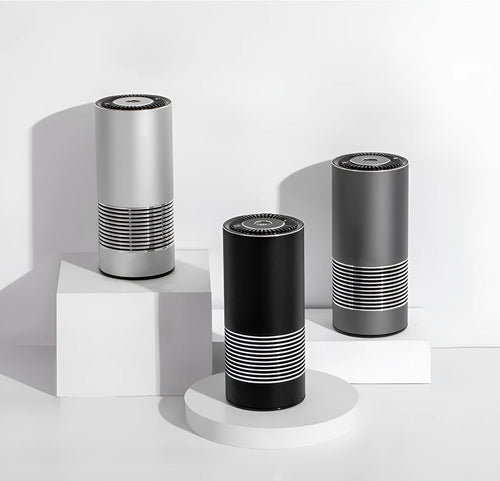 Compact cylindrical car air purifier in metallic grey with aluminium alloy casing.