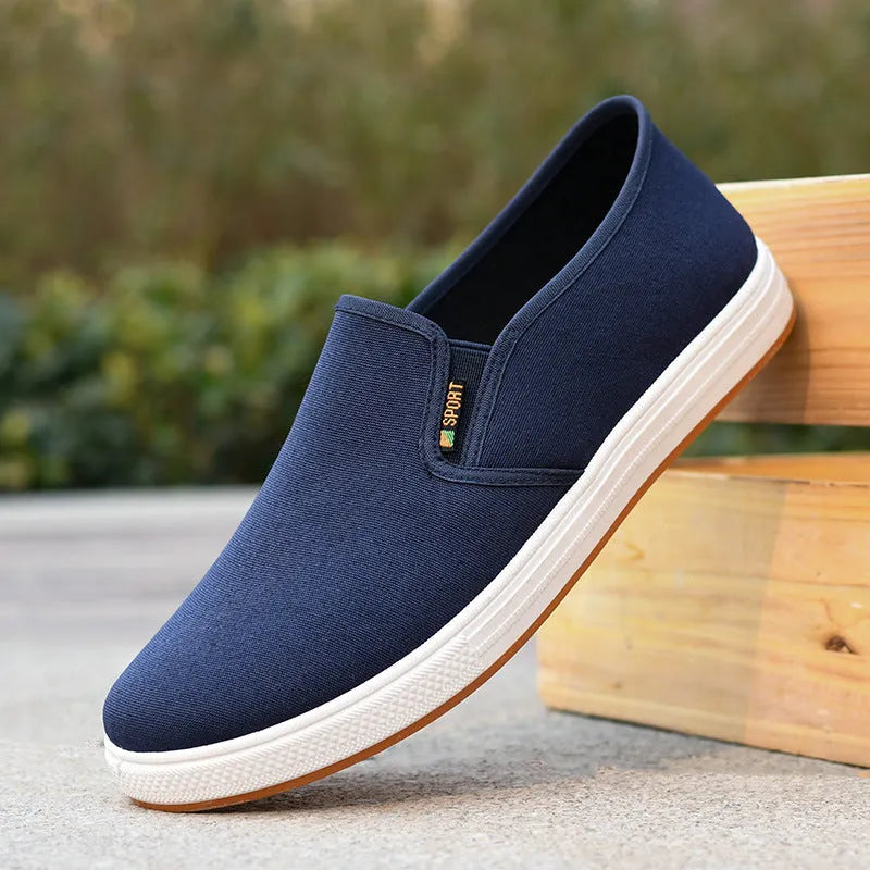 Men's black low-top slip-on canvas shoes with a round toe and composite sole on a white background.