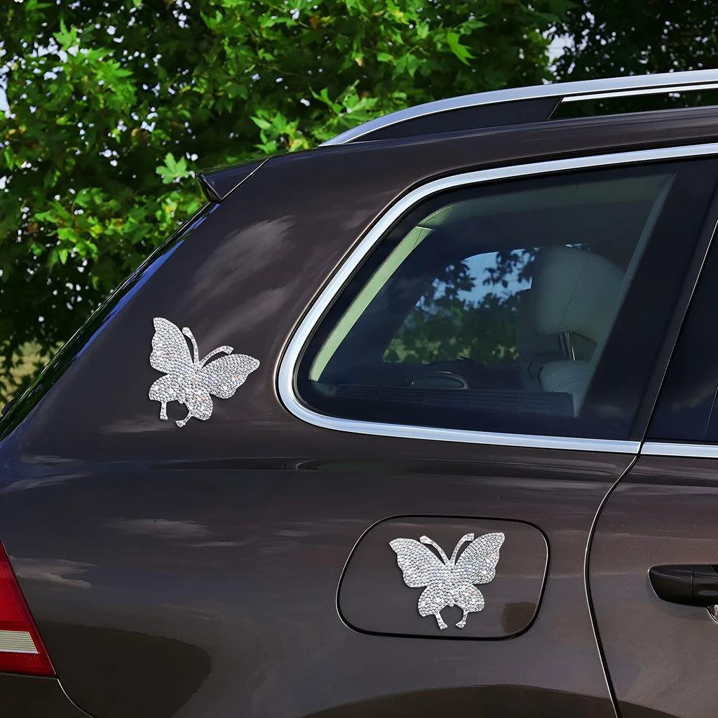 Close-up of a diamond-encrusted glass car sticker in a butterfly or bear claw design on a white background.
