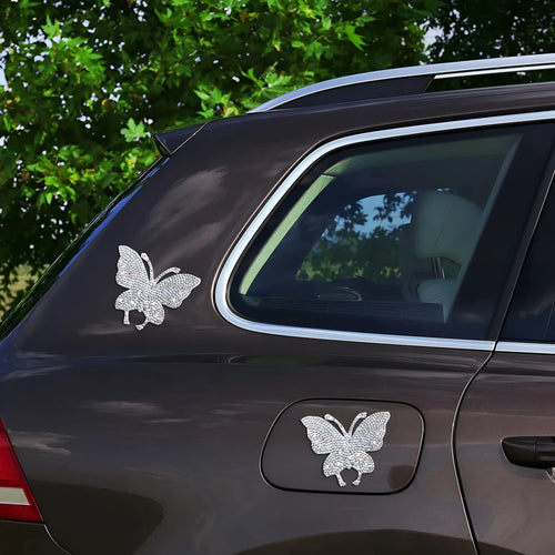 Close-up of a diamond-encrusted glass car sticker in a butterfly or bear claw design on a white background.