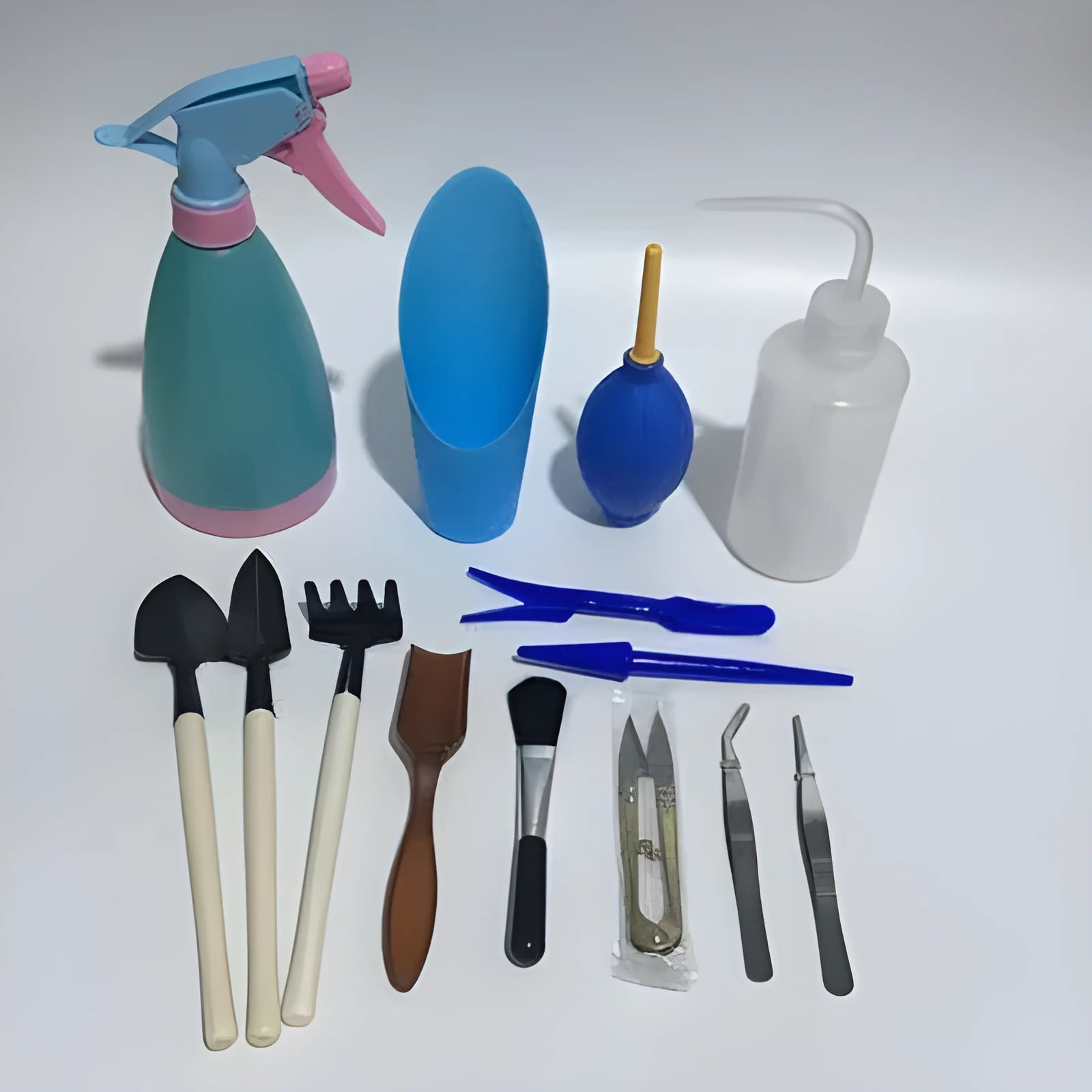 14-piece plastic succulent gardening tool set showing drip kettle, mini shovels, tweezers, and brush on a table.