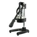 Black or white manual cast iron citrus juicer with stainless steel funnel on a kitchen counter.